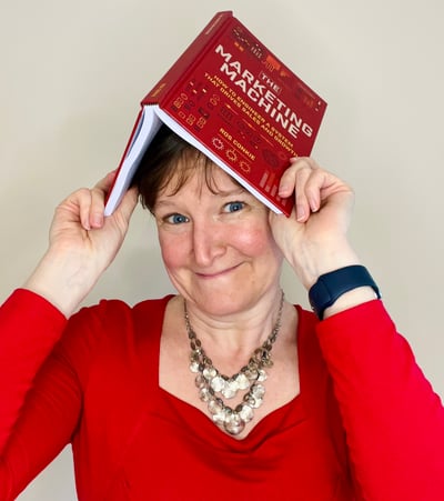 Ros holding the book on her head and a bemused expression.