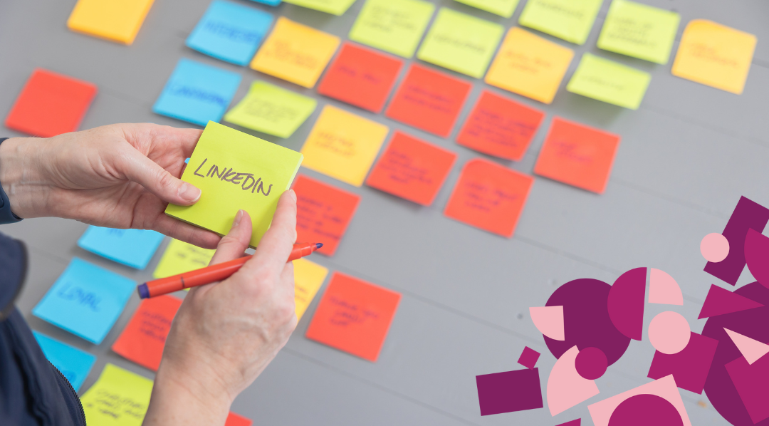 A table full of post-it notes with someone holding a post-it that reads 